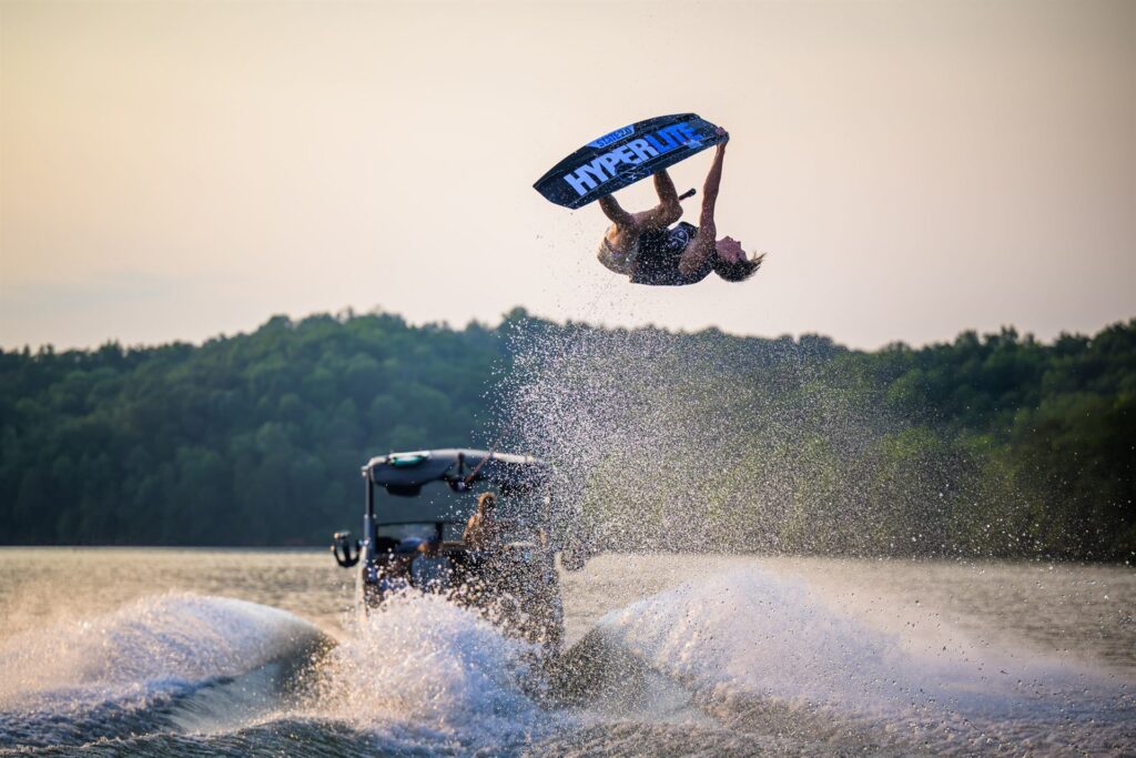 Rider executando manobra aérea no wakeboard atrás do barco