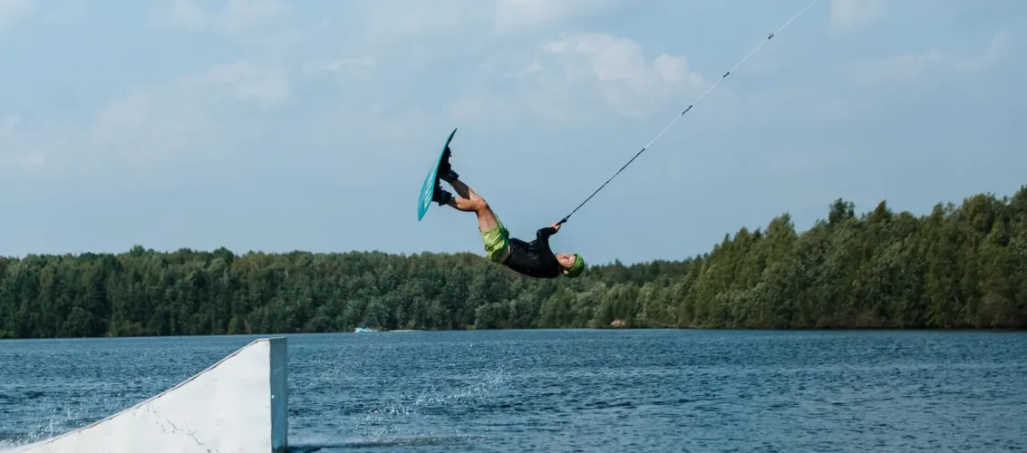 Praticante em pé sobre prancha executando manobra no cable park, ilustrando o que é o esporte wakeboard